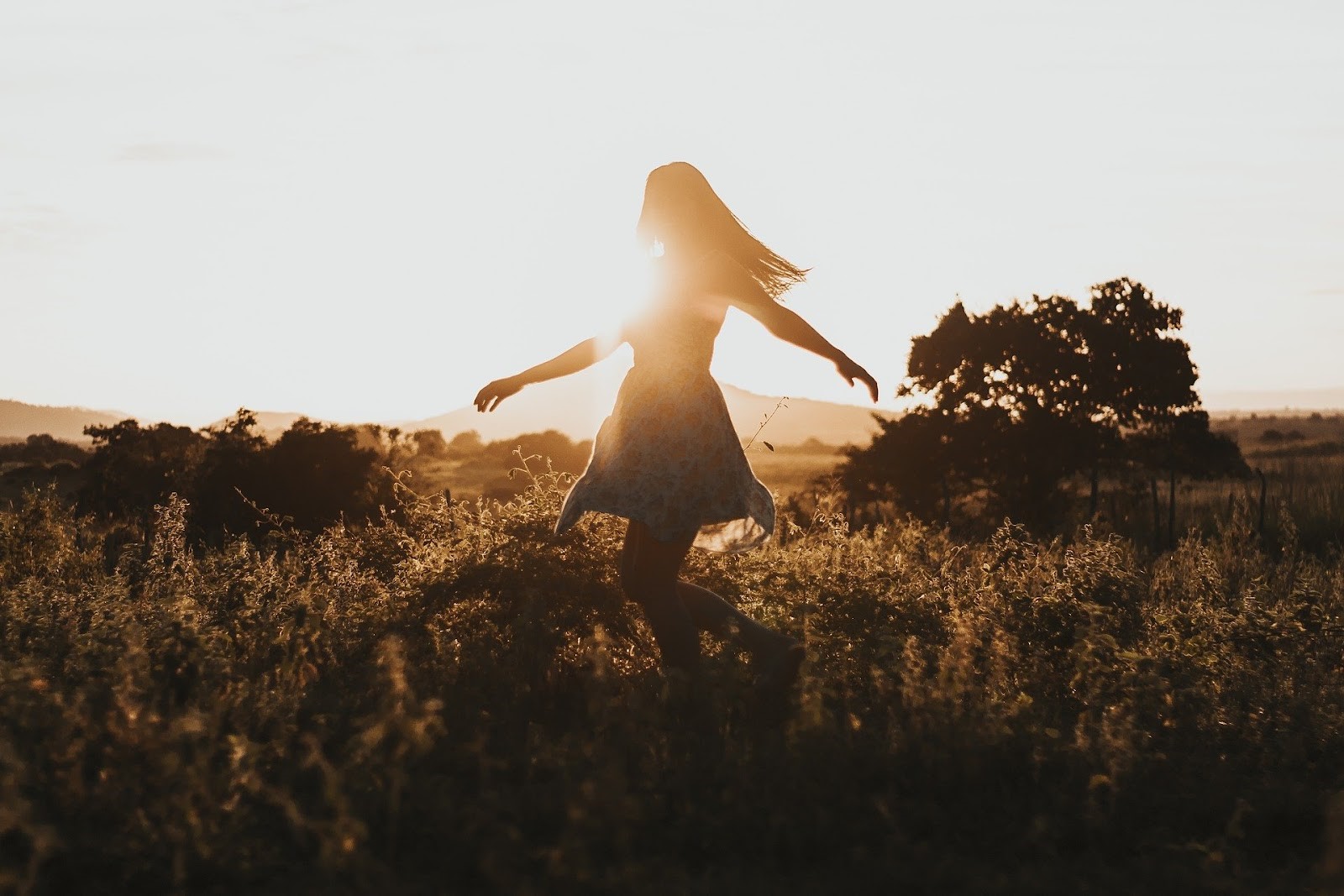Girl walking in the fields with arms outstretched